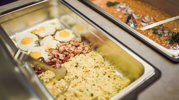 Un bufé con diversas opciones de comida, como huevos, tocino y arroz.