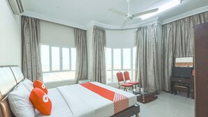 A hotel room with a bed, a ceiling fan, a TV, and a desk. - Super OYO 111 Al Thabit Hotel (Sur)