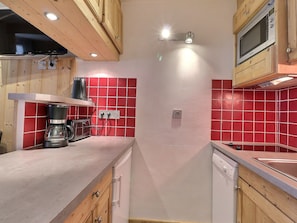 A kitchen with wooden cabinets, a coffee maker, a microwave, and red-tiled backsplash.