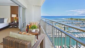 A balcony with a view of a marina, a bed, a table with a plant, and a sofa. - 20th Floor Ocean & Marina Views at The Ilikai! Washlet! FREE Parking & Wi-Fi! (Honolulu)
