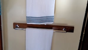A towel rack with two white towels, one with a blue stripe, mounted on a wooden wall. - Mali Guest House (Mombasa)