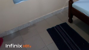 A bedroom with a wooden bed frame, a white mattress, a blue bedspread, a black rug, a wooden headboard, a wall-mounted mirror, and a towel hanging on a metal towel rack. - Mali Guest House (Mombasa)