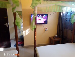 Une chambre d’hôtel avec un lit, un téléviseur fixé au mur et une petite table.