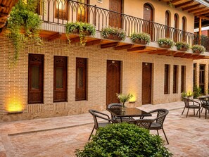 A courtyard with brick walls, wooden balconies, and outdoor seating. - AYUB Modern & Heritage HOTEL (Bukhara)