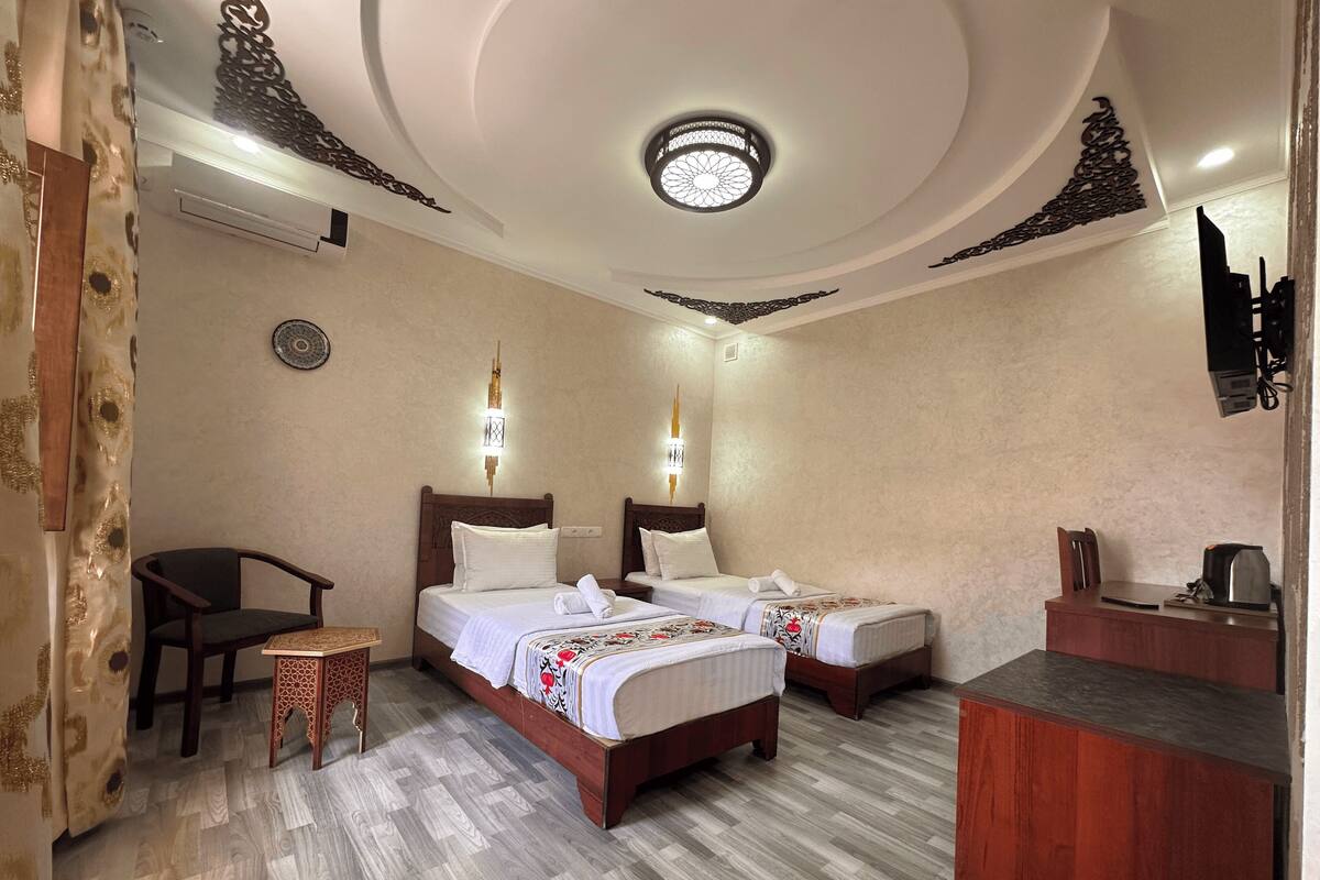 A hotel room with two beds, a small table, a chair, and a desk with a coffee maker.