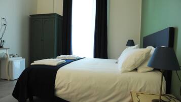 A hotel room with a bed, a nightstand, a lamp, and a wardrobe.