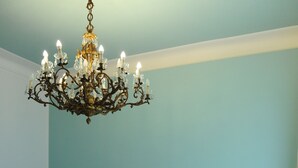 A bedroom with a bed, a blue headboard, a chandelier, bedside tables with lamps, and a blue armchair. - Milano Dreams (Milan)