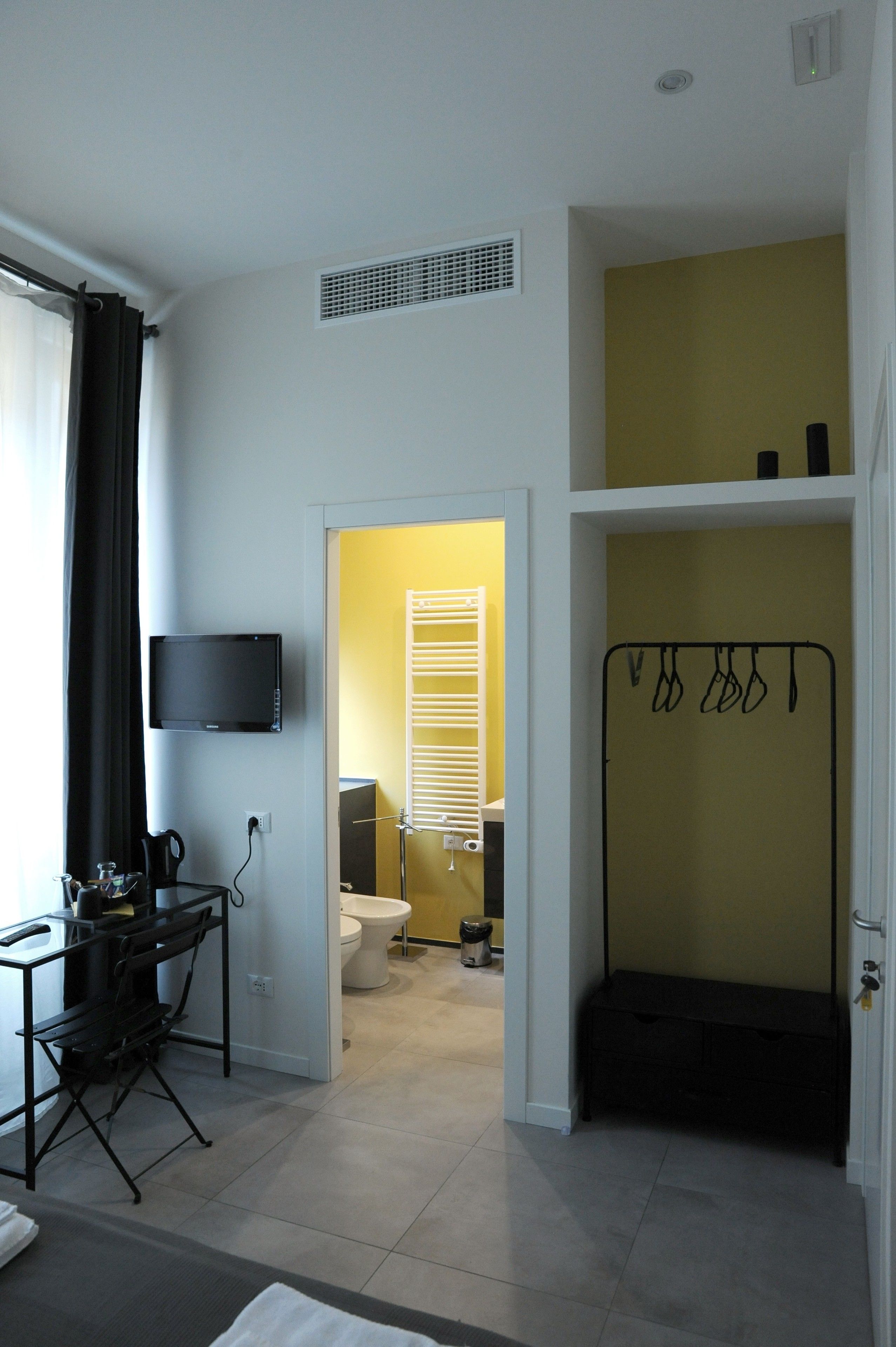 Ein Hotelzimmer mit Schreibtisch, Flachbildfernseher, Bett, Badezimmer mit Toilette und Dusche sowie Ablagefläche für Toilettenartikel.