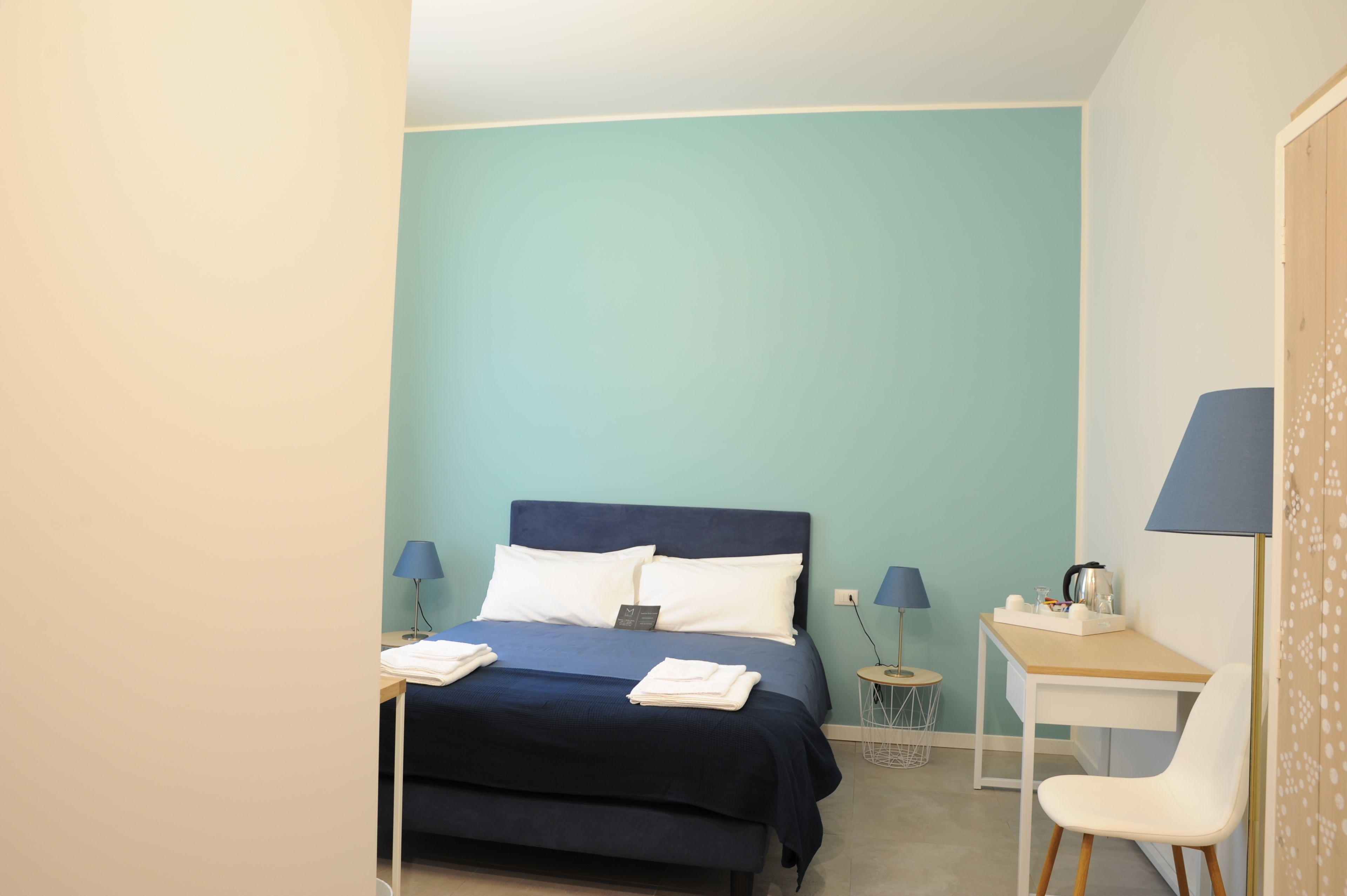 Un dormitorio con cama, escritorio, silla y dos lámparas.