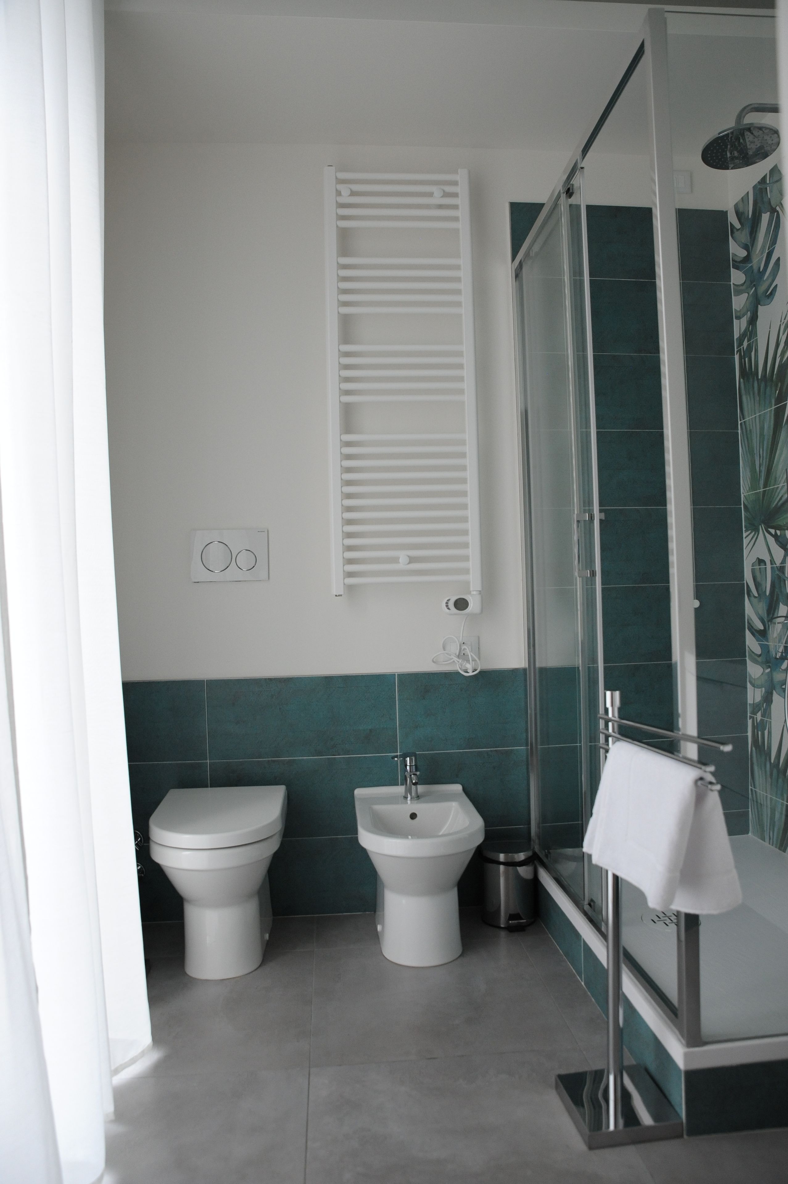 Un bagno con toilette, bidet e doccia con pareti in vetro.