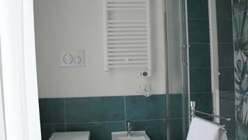 Un bagno con toilette, bidet e doccia con pareti in vetro.