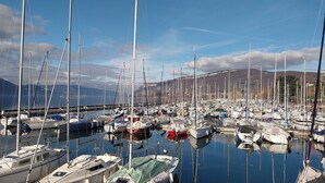 Ein Yachthafen mit verschiedenen Booten und Yachten, umgeben von Bergen und blauem Himmel.