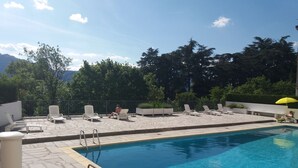Ein Schwimmbecken mit Liegestühlen und einer kleinen Sonnenterrasse.