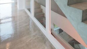Ein modernes Interieur mit einer Treppe, Glaswänden und einem glänzenden Boden.