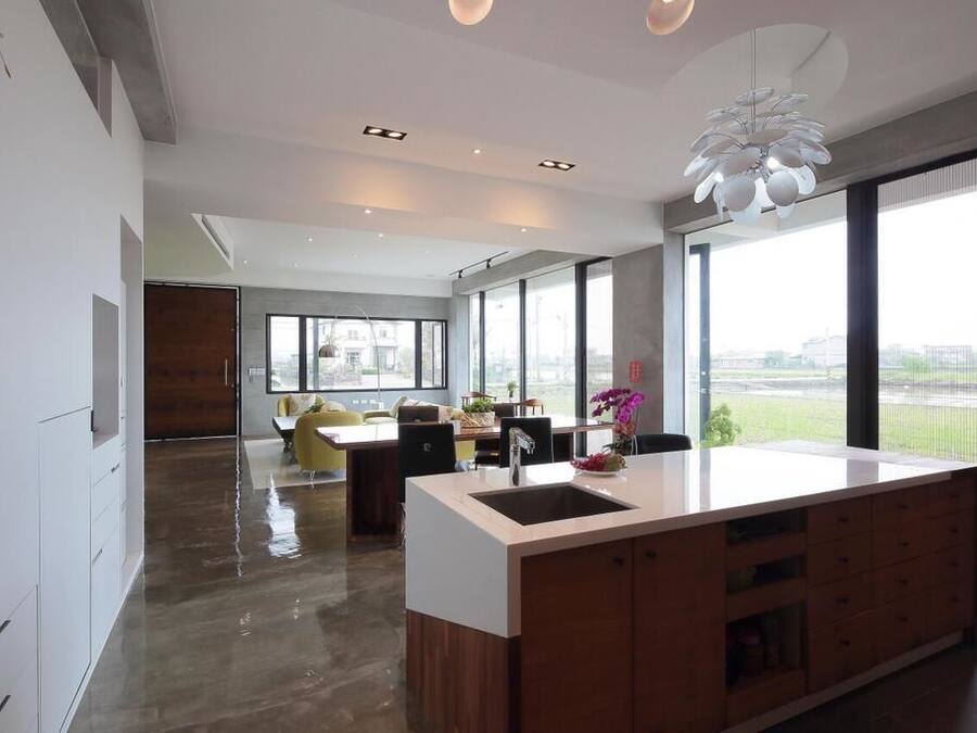 A modern kitchen with a large island, a dining area with yellow chairs, and large windows offering a view of the city.