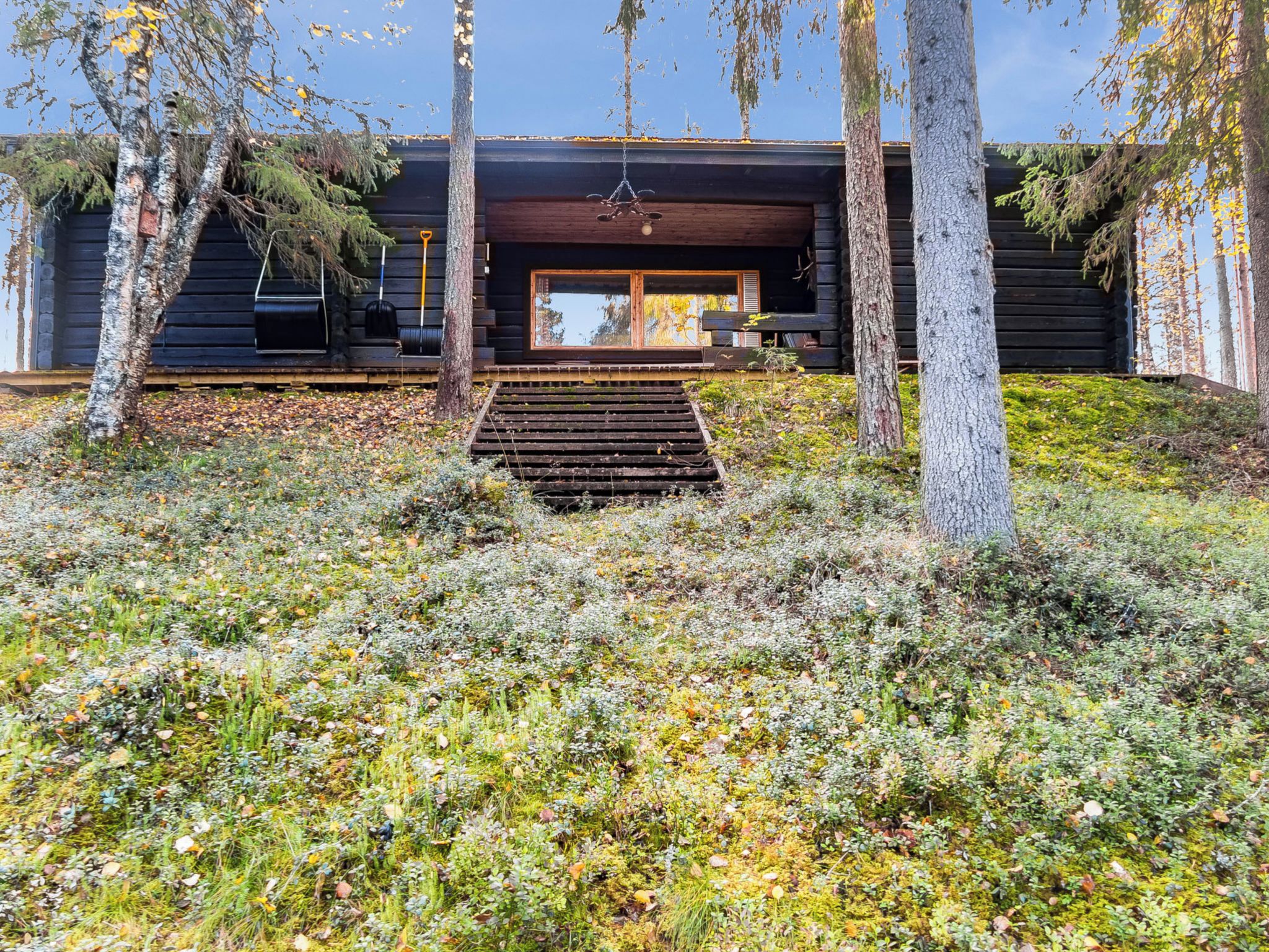 A modern log cabin with a wooden staircase leading to a large window.