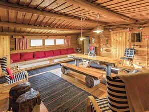 A wooden cabin interior with a sofa, dining table, and benches.