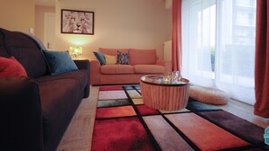 A living room with a brown sofa, a pink sofa, a coffee table, and a colorful rug.