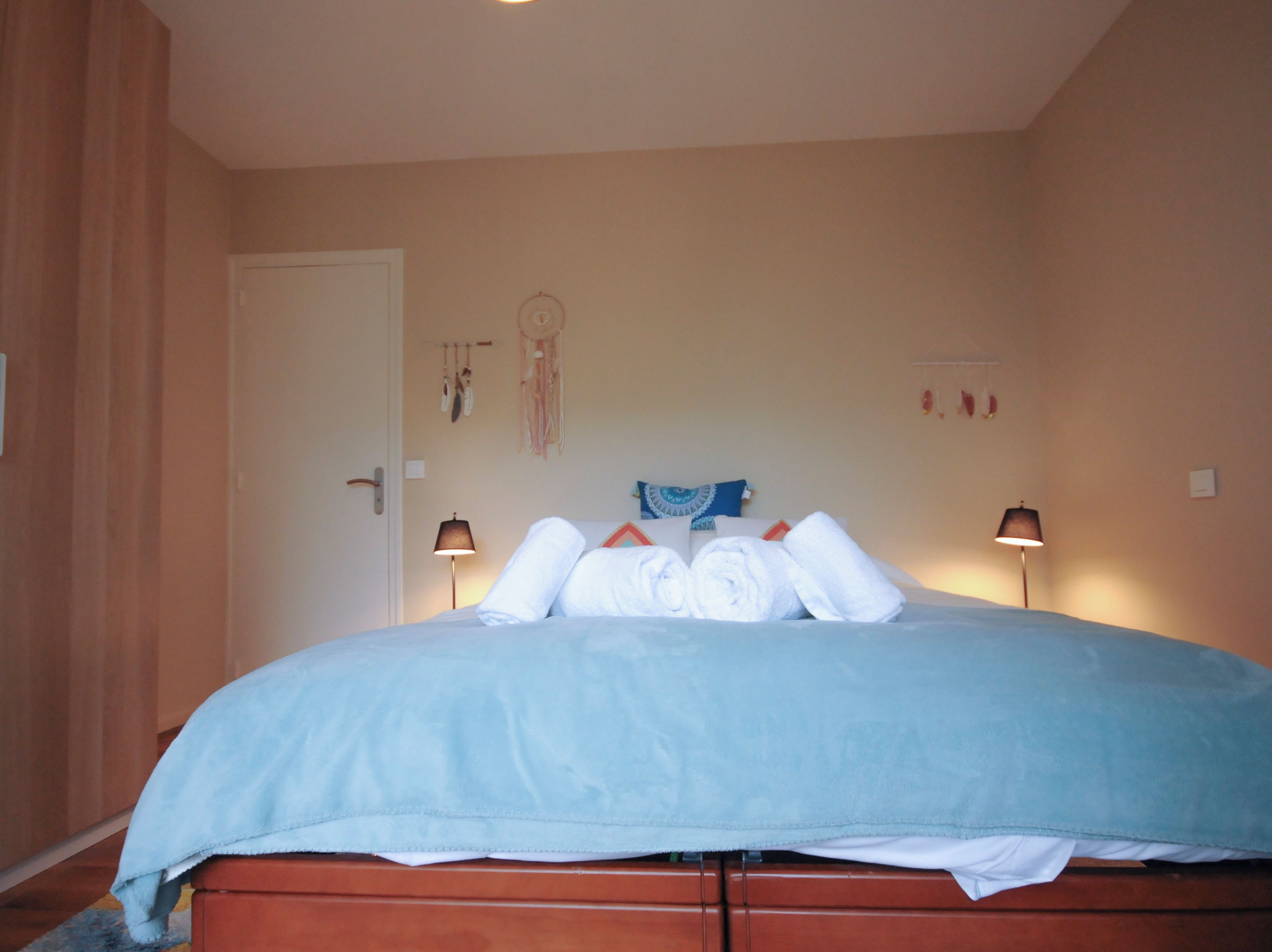 Een slaapkamer met een bed, twee bedlampen, een deur en een decoratie aan de muur.