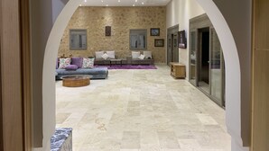 A spacious living area with a stone wall, a sofa set, a coffee table, and a television. - Luxury villa with private pool not overlooked. (Fès)