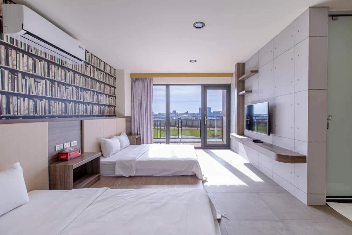 Una habitación de hotel moderna con una amplia estantería, un televisor de pantalla plana y un balcón con vistas a la ciudad.