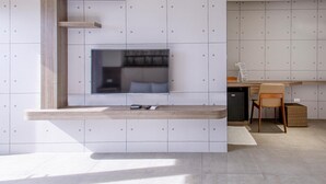 A modern kitchen with a built-in TV, wooden shelves, and a dining area with a chair and table. - Sharp bnb (Magong)