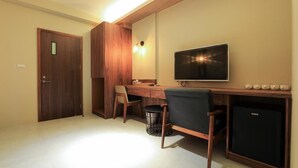 A compact room with a wooden desk, a chair, a television, and a small refrigerator. - Sharp bnb (Magong)