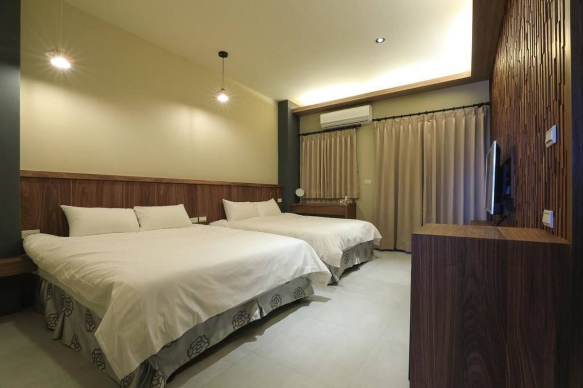 Habitación de hotel con dos camas, cabecera de madera, escritorio y televisor.