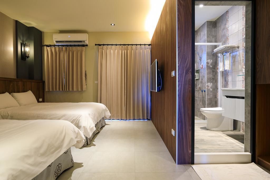 Une chambre d’hôtel avec deux lits, un espace douche et un téléviseur fixé au mur.