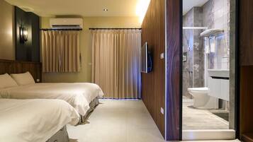 Une chambre d’hôtel avec deux lits, un espace douche et un téléviseur fixé au mur.