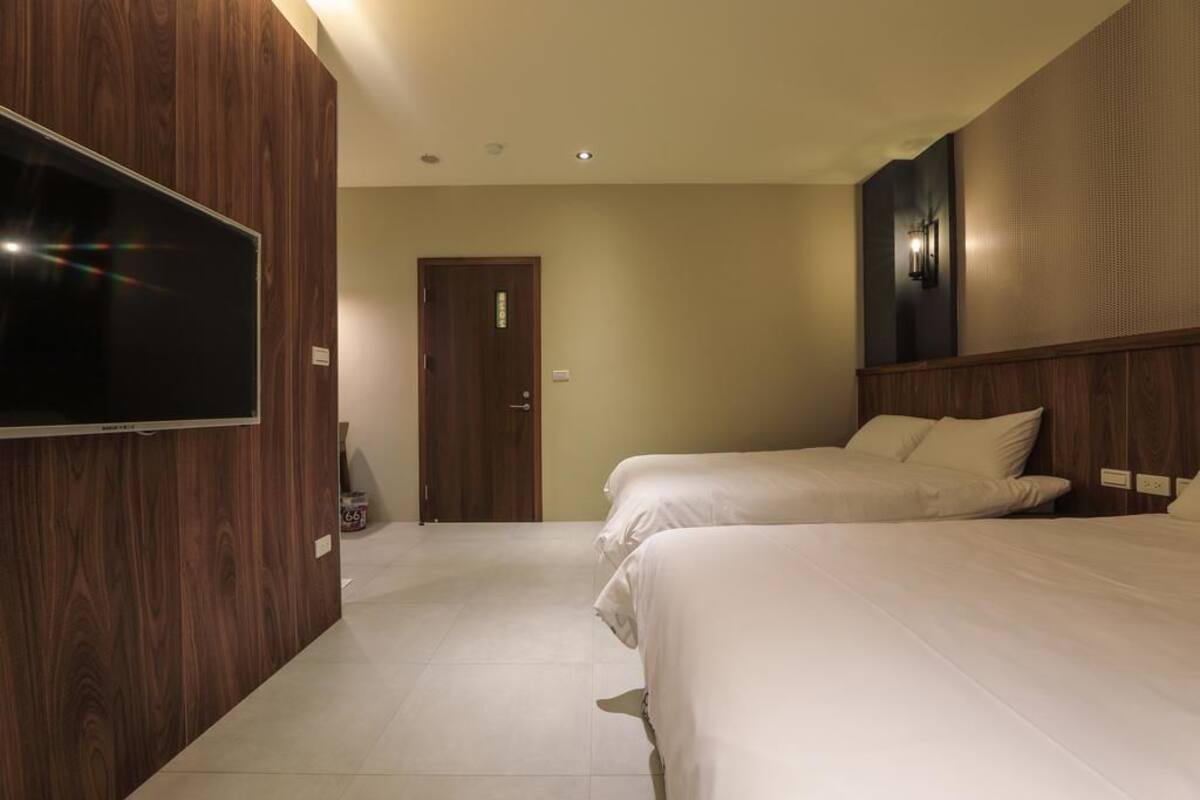 Habitación de hotel con dos camas, televisión y una puerta.