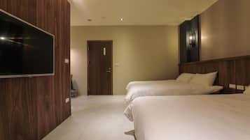 A hotel room with two beds, a TV, and a door.
