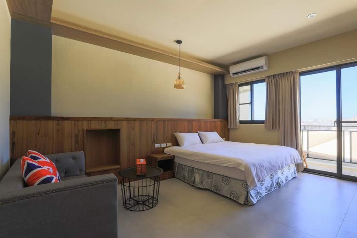 Habitación de hotel con cama, sofá, una mesita y un ventanal con vistas.