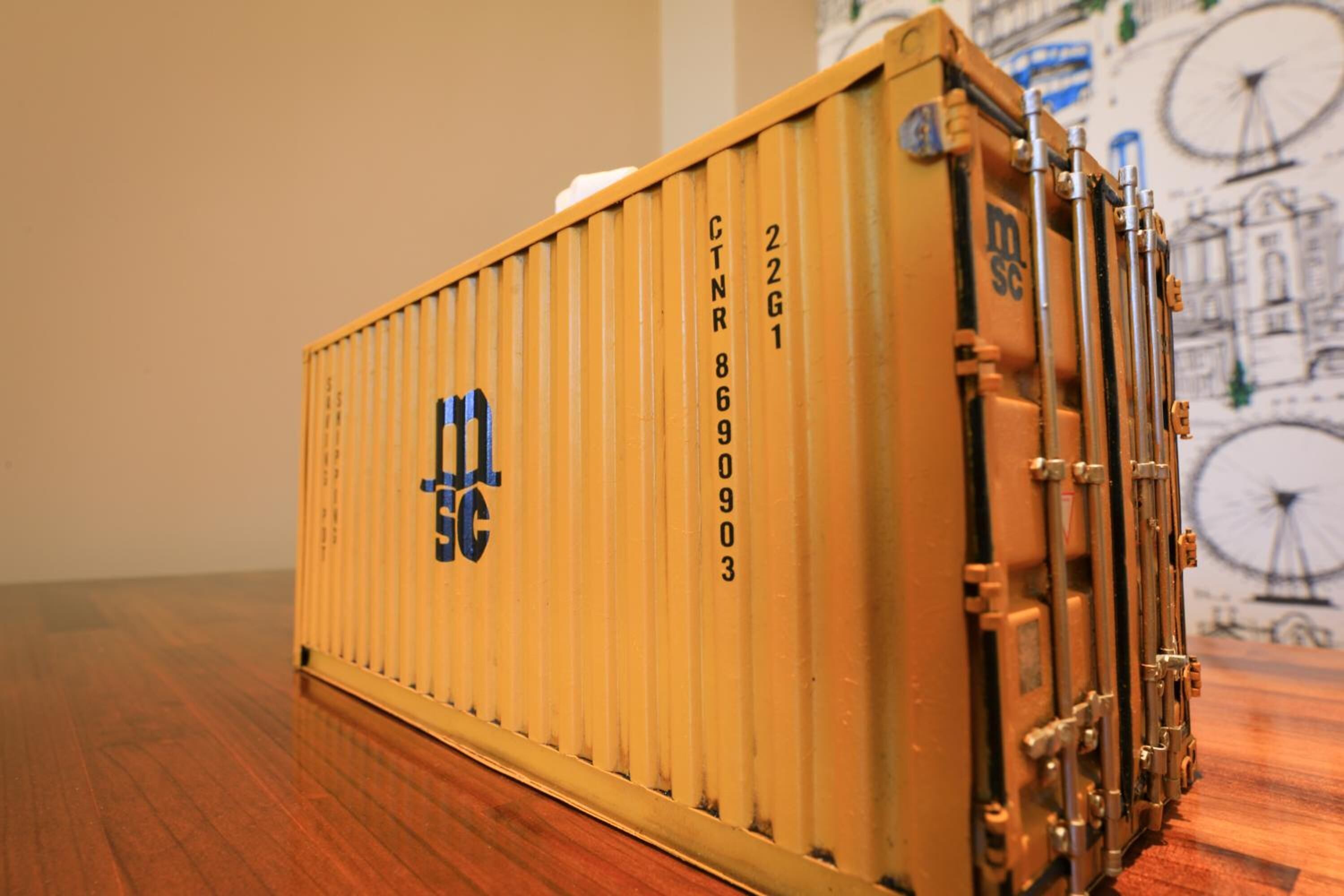 A model of a yellow shipping container with the letters 'MSC' and numbers '22G1' on it.