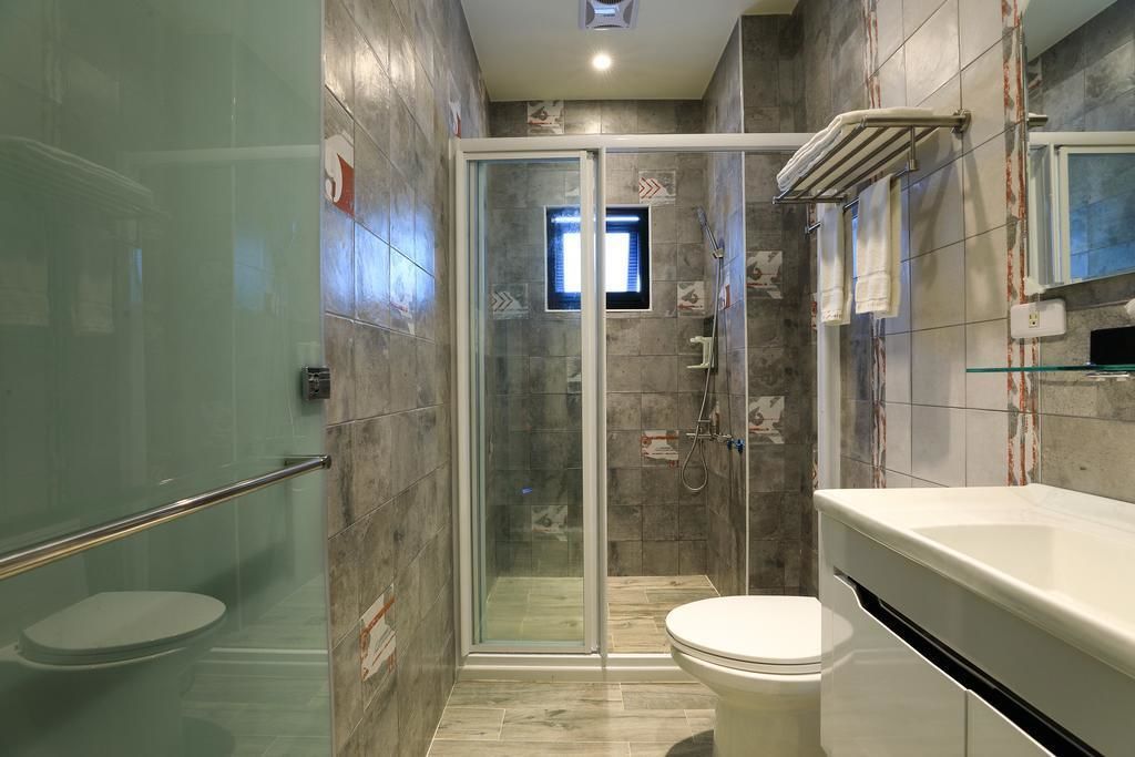 Ein modernes Badezimmer mit einer gläsernen Duschkabine, einer weißen Toilette und einem Waschtisch mit Spiegel.