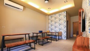 A room with multiple wooden tables and benches, an air conditioning unit, and a patterned wallpaper. - Sharp bnb (Magong)
