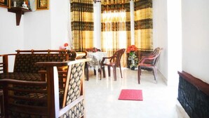 A dining area with a table and chairs, a red mat on the floor, and a window with striped curtains. - Mount view family rest & cottage (Hildummulla)
