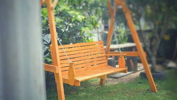 A wooden swing set in a garden with a bench and potted plants in the background. - Mount view family rest & cottage (Hildummulla)