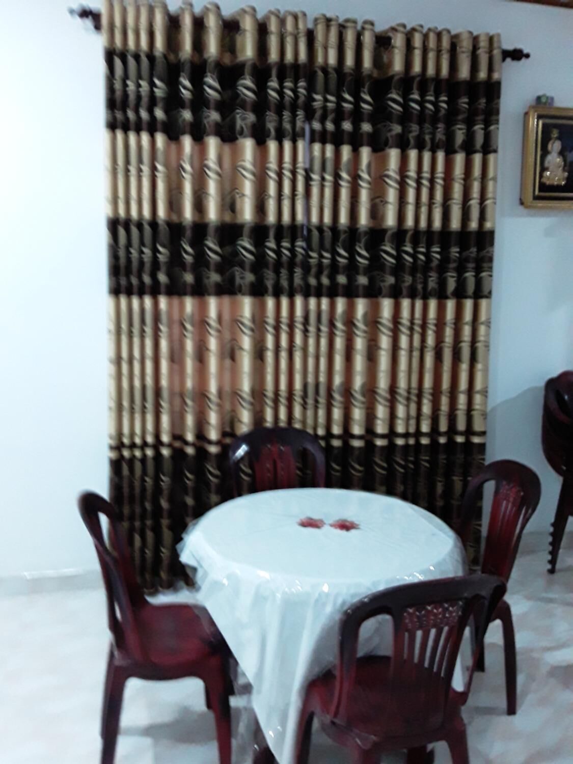 Un espace repas avec une table ronde recouverte d’une nappe blanche, entourée de chaises en bois.