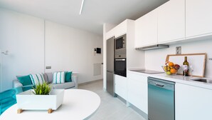 A modern kitchen with white cabinets, a dishwasher, and a countertop with a fruit bowl.