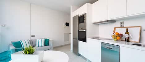 A modern kitchen with white cabinets, a dishwasher, and a countertop with a fruit bowl.