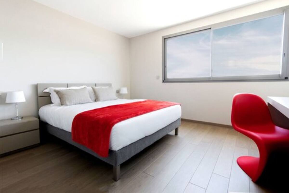 A hotel room with a bed, a desk, and a window.