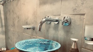 Un bagno con un lavabo blu in ceramica di grandi dimensioni, un rubinetto moderno e un dispenser di sapone su un piano di lavoro in legno.