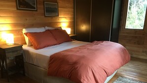 Camera da letto in una baita di legno, con un letto, comodini e una finestra.
