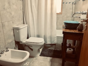 Een bad/douchecombinatie, een haardroger, een bidet, handdoeken
