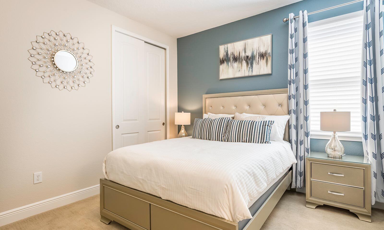 A bedroom with a bed, bedside tables, a mirror, and a window with curtains.