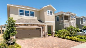 A two-story house with a garage, stone accents, and a well-maintained lawn.