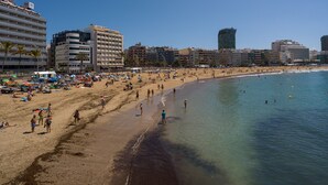 Una playa con un hotel al fondo.