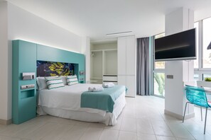 Ein modernes Hotelzimmer mit Bett, Fernseher, Schreibtisch und Badezimmer.