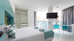 Una habitación de hotel moderna con una cama grande, televisor, balcón con vistas y armario.